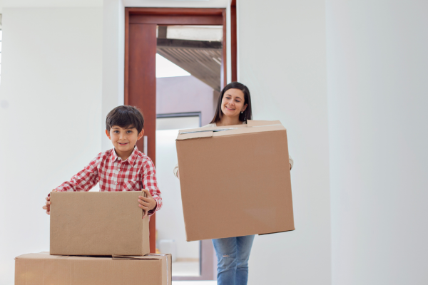 Woman and kid carrying cardboard boxes.