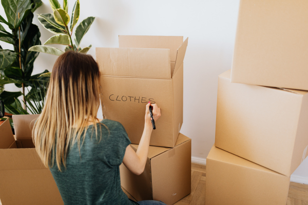 Woman writing on cardboard boxes with pen.