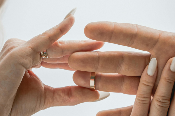 Close up of woman taking off of mans hand a wedding ring.