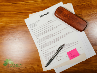 Top view of divorce papers and pen on wooden table. The Family Law Group logo.