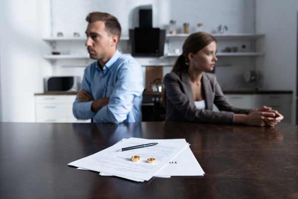 Couple sitting with their backs to eachother. Documents on table. 