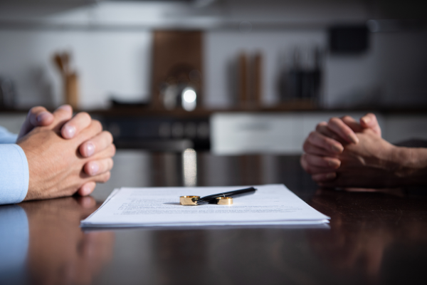Man and woman with hands over table with document and pen.