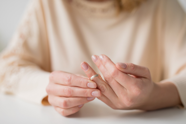 Close-up of woman taking of weeding ring.